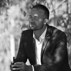 Deux photos en noir et blanc d'un homme en blazer : au téléphone près d'un mur de planches blanches, et assis dehors un téléphone à la main