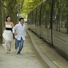Couple courant main dans la main sur un chemin bordé d'arbres, le long d'un tramway moderne à Bordeaux