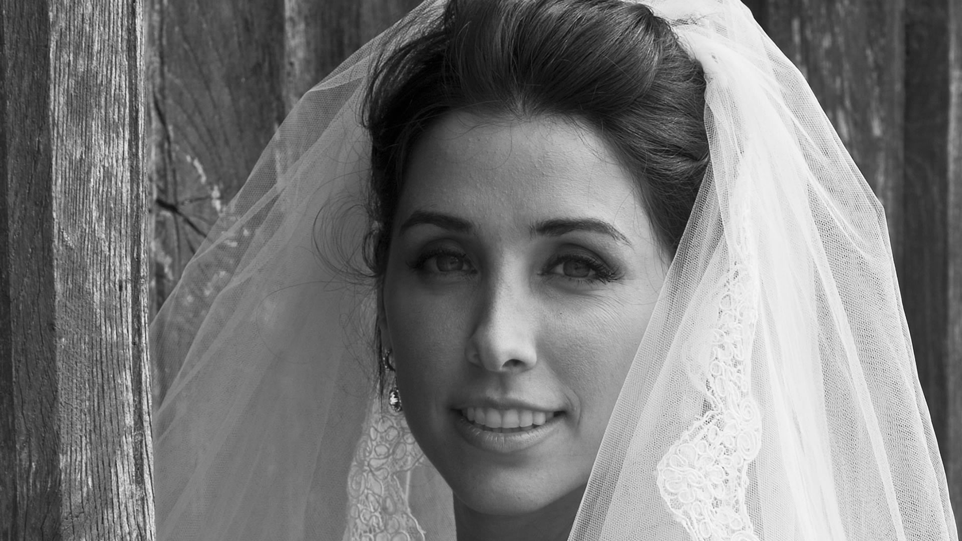 Portrait de mariée en noir et blanc en gros plan, mettant en valeur le voile, les détails en dentelle et l'expression de la mariée